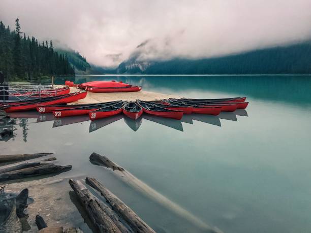 istock Red boats on the river shore with clear water and a cloudy sky 1455762780