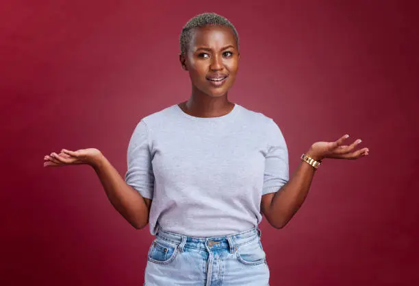 Confused, question and why black woman on studio red background, body language and facial gesture for risk decision, shrug and reaction. Uncertainty, unsure and frustrated model, doubt and confusion