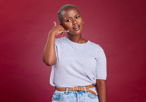 istock Black woman, annoyed and hand phone call sign by studio background for question, communication or network. Model, woman and call me symbol with frown while frustrated, thinking or confused in tech 1455764290