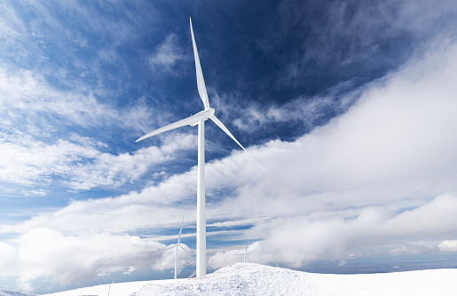 Wind turbines on snow covered mountain.