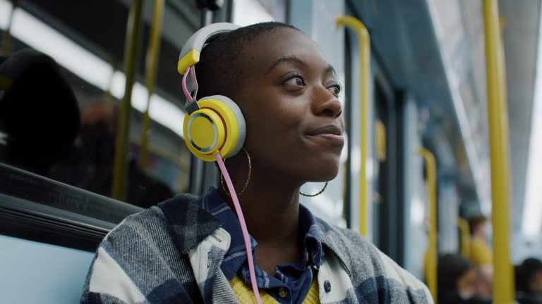 Smiling Woman Listening to Music Using Headphones While Traveling by Subway Train. Stylish Female Using Public Transport to Get Home, Enjoying her Time and Getting into her Personal Space