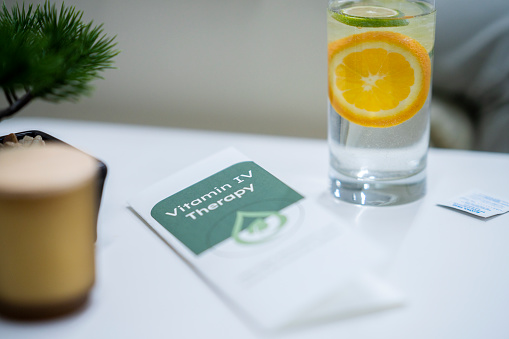 An information pamphlet and water with lemon and lime are seen sitting out on a table at a Vitamin clinic.  The table is set for patients to feel comfortable and at ease while receiving their treatments.