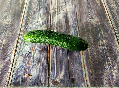 Whole fresh cucumber on a wooden table. Close-up