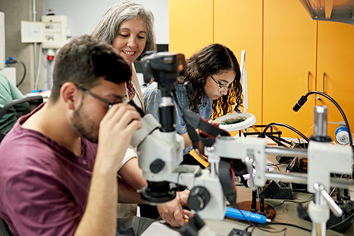 Educador sonriente que ayuda a los estudiantes de STEM en el laboratorio técnico photo