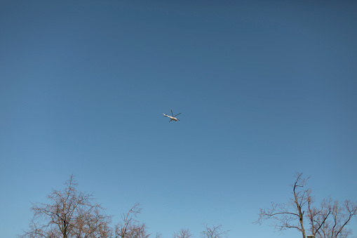 Small helicopter in blue sky. Aircraft. Helicopter flight over forest.