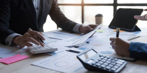 istock Business People Meeting using laptop computer,calculator,notebook,stock market chart paper for analysis Plans to improve quality next month. Conference Discussion Corporate Concept 1455769332