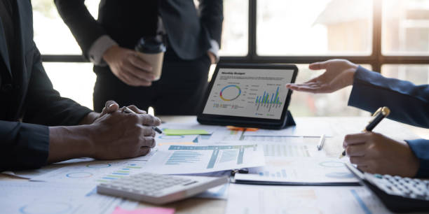 istock Business People Meeting using laptop computer,calculator,notebook,stock market chart paper for analysis Plans to improve quality next month. Conference Discussion Corporate Concept 1455769357
