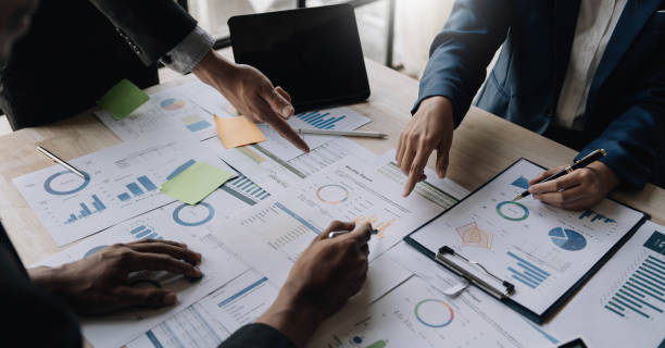 istock Business People Meeting using laptop computer,calculator,notebook,stock market chart paper for analysis Plans to improve quality next month. Conference Discussion Corporate Concept 1455769401