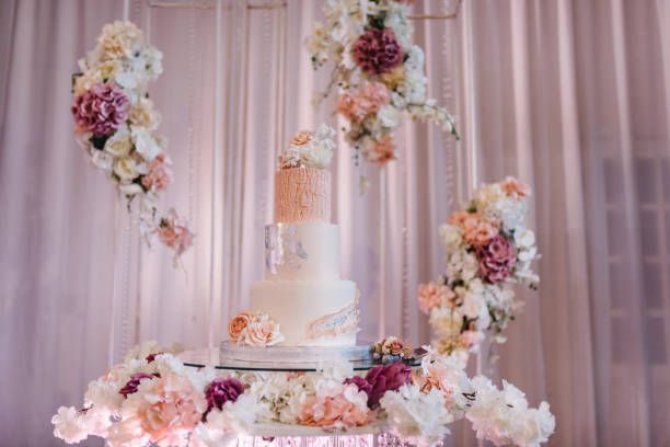 Delicious wedding reception. Birthday cake on a background party. Wedding cake on a background of an arch decorated with flowers for a banquet. Celebration concept. Trendy Cake.