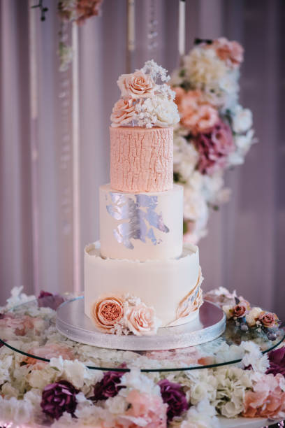 istock Delicious wedding reception. Birthday cake on a background party. Wedding cake on a background of an arch decorated with flowers for a banquet. Celebration concept. Trendy Cake. 1455769445