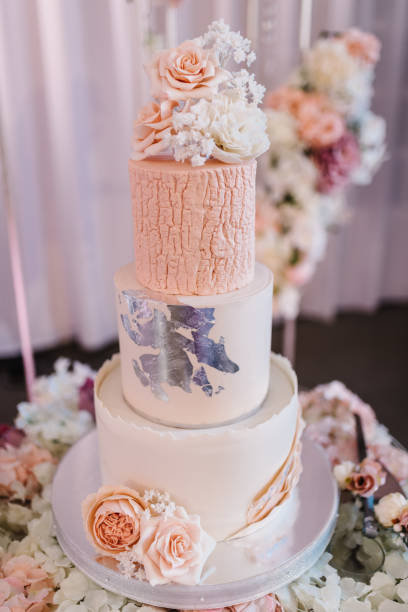 istock Delicious wedding reception. Birthday cake on a background party. Wedding cake on a background of an arch decorated with flowers for a banquet. Celebration concept. Trendy Cake. 1455769469