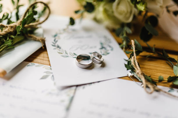 stylish rings, flowers on wooden table background. letters from the bride and groom. vows. engagement. luxury marriage and wedding accessory concept. - wedding stockfoto's en -beelden