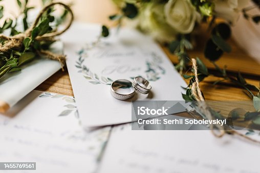 istock Stylish rings, flowers on wooden table background. Letters from the bride and groom. Vows. Engagement. Luxury marriage and wedding accessory concept. 1455769561