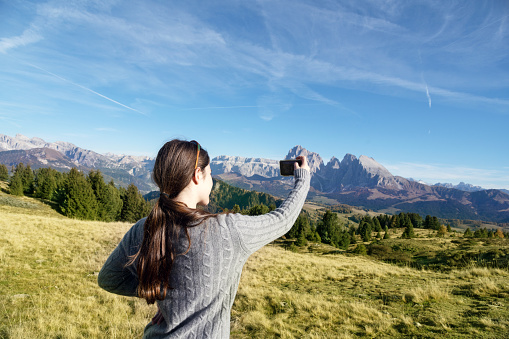 Young teenage girl taking photo from mountains. Photo taken in Dolomites / Italy