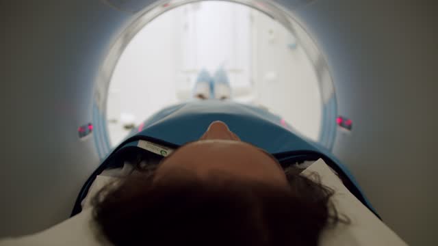 Woman during CT scanning procedure. Functioning MRI machine in a medical room.