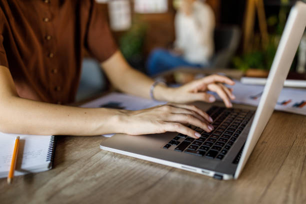 istock Young woman sitting at her desk, typing data on laptop 1455773115