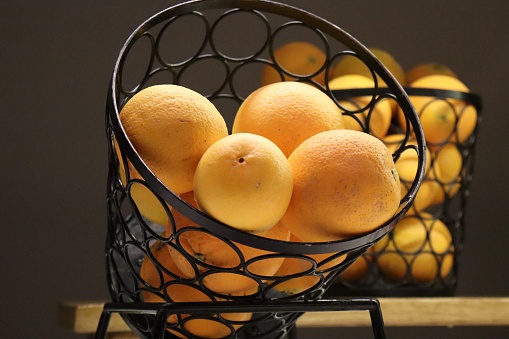 whole oranges in a black wire basket