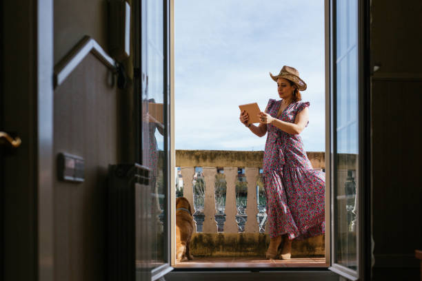 istock Stylish woman using a digital tablet while standing in a balcony at home. 1455774477