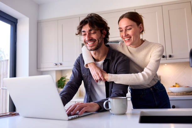 istock Couple At Home Looking At Laptop On Counter In Kitchen Together 1455774754