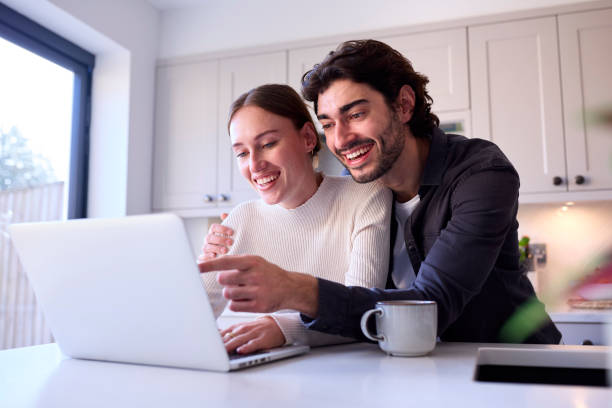 istock Couple At Home Looking At Laptop On Counter In Kitchen Together 1455774758