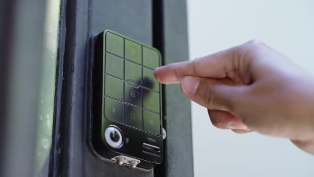 A hand pressing security code on the keypad of the apartment electronic door lock and entering
