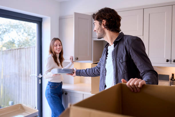 istock Young Couple Moving Into New Home Unpacking Boxes In Kitchen Together 1455775504
