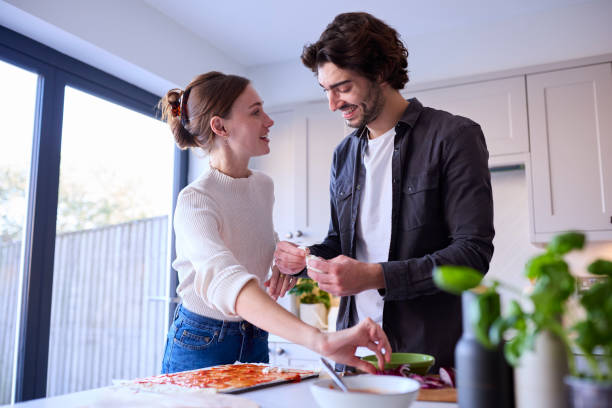 istock Couple In Kitchen At Home Making Homemade Pizza Together 1455777112