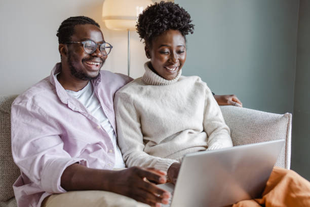 istock Young African-American couple using laptop at home 1455777477