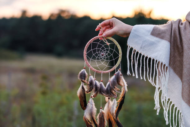 istock Woman with poncho holding dreamcatcher during sunset 1455777478