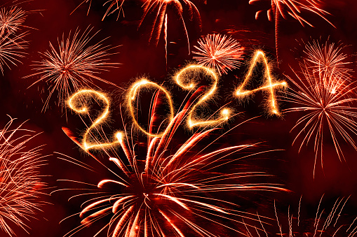 New Year fireworks and 2024 sign made of sparkler trace on a night sky background.