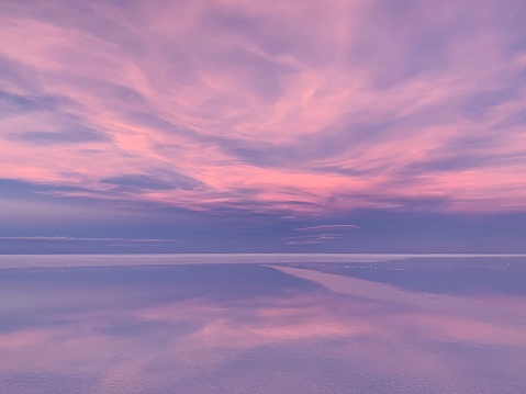 Beautiful sunset sky clouds pink purple over sea water.