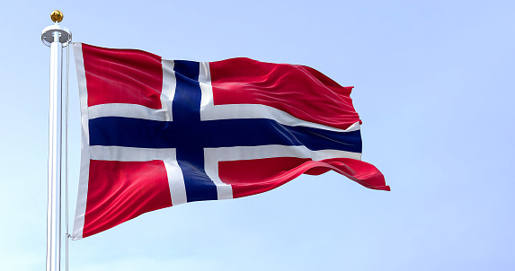 Norway national flag waving in the wind on a clear day. Red field with a blue cross with white outline. Realistic 3D illustration. Rippled textile