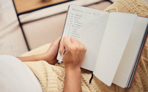 istock Book, hand and woman writing list in her notebook while relaxing with ideas and future vision. Self love, self care and female hands write motivational list in her journal for mental health 1455780533