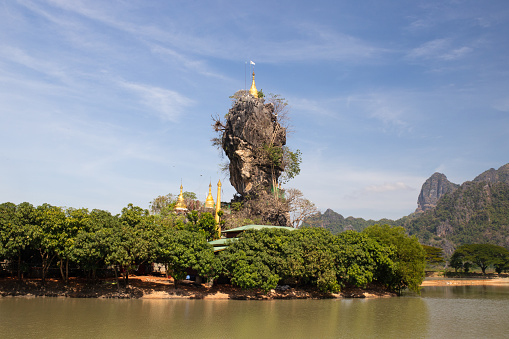 Kyaut Ka Latt Pagoda in Hpa-An . A beautiful pagoda sits atop a rock amongst stunning scenery