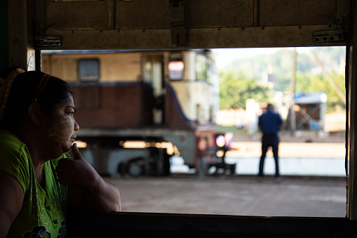 A portrait of a local woman sitting in the cab of an older train car in Southern Myanmar. The rail lines and equipment are failing into disrepair. Myanmar