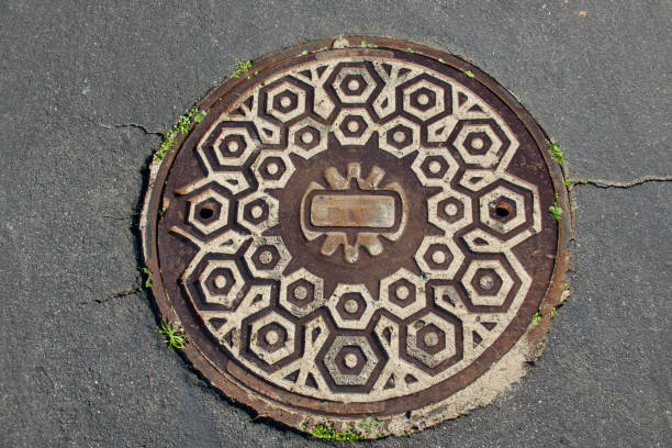 Closeup of metal manhole cover with Aztec geometric design Closeup of metal manhole cover with Aztec geometric design sewer lid stock pictures, royalty-free photos & images