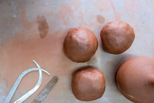 Wet clay balls and  tools for ceramic art and pottery  in the pottery workshop. Top view with copy space. Background for ceramic art, ceramic studio, art and craft.