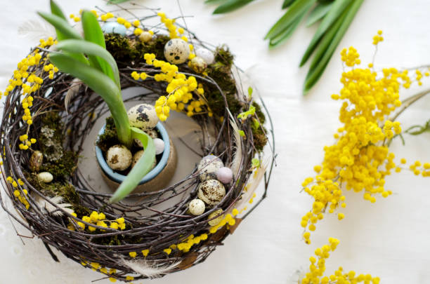 istock Easter decorative wreath and branches of yellow bright mimosa on the table 1455787803