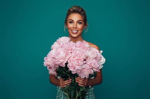 Beautiful emotional woman holding bouquet of flowers