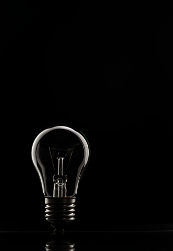The concept of saving electricity. A tungsten light bulb on a black background