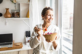 Beautiful woman eating healthy vegetable salad wearing bathrobe