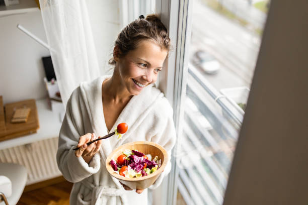 istock Beautiful woman eating vegetable salad wearing bathrobe 1455801558