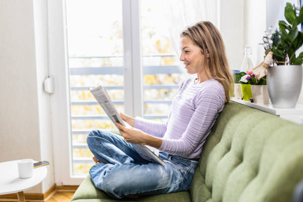 istock Young woman reading a newspaper and holding a coffee cup 1455801571