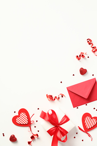 Happy Valentine's Day poster design. Flat lay Valentine gift box, hearts, letter envelope, confetti on white table.