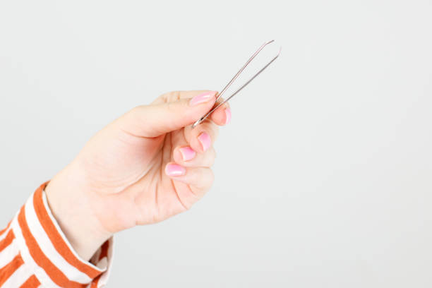 istock eyebrow tweezers in hand close-up 1455808324