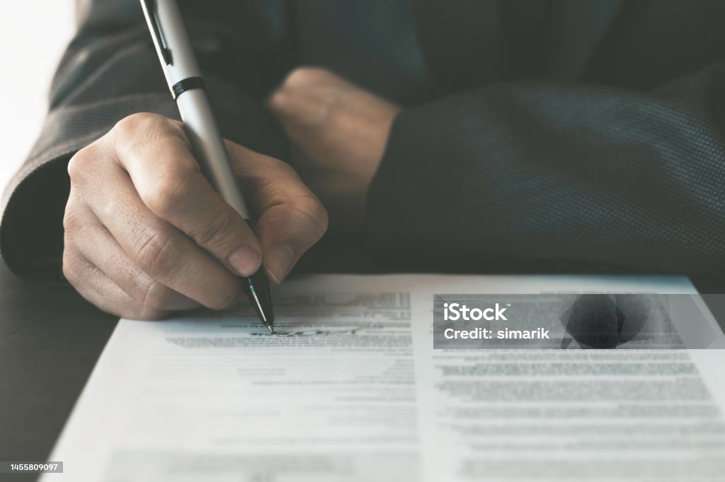 Signing Contract Paper Unrecognizable adult wearing jacket is signing contract paper. Document Stock Photo