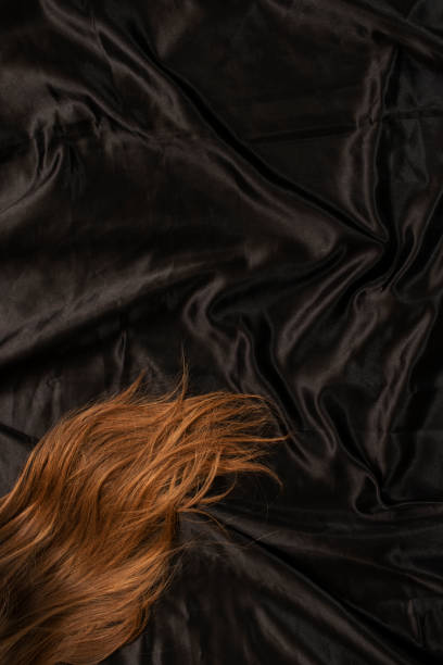 istock Female red hair on black bed sheet. 1455809141