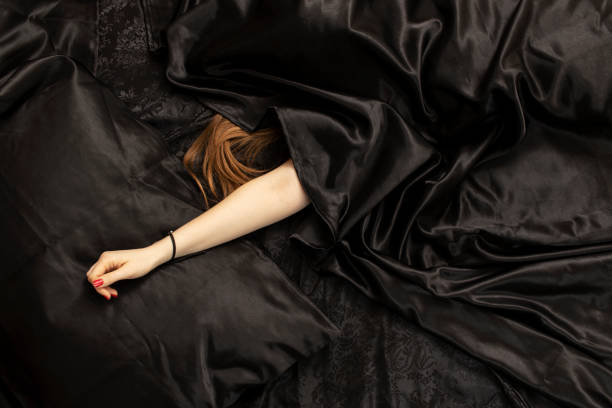 istock Female red hair and a hand on black bed sheet. 1455809151
