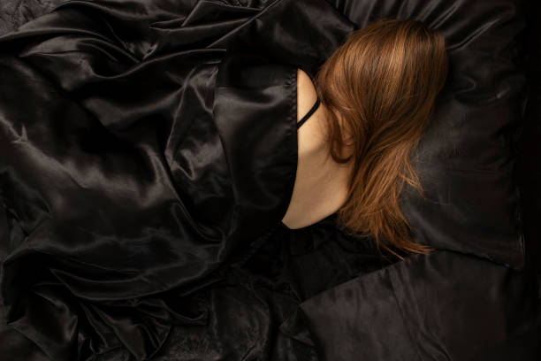 istock Woman sleeps in a bed on black bed sheet. 1455809164