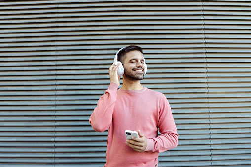Photo of a young man listening to music and holding a smart phone